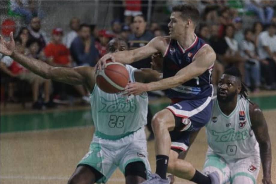 Hansel Atencia, de Titanes de Barranquilla, ante la marca de dos jugadores de Toros del Valle en el cuarto partido de la final de la Liga Profesional de Baloncesto.