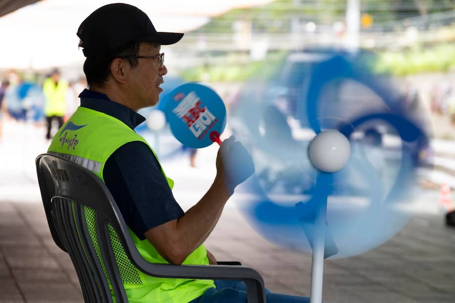 Un responsable de seguridad se sienta con un ventilador para refrescarse del calor extremo en la zona de refrigeración de la plaza Cheonggye en Seúl, Corea del Sur, el 4 de agosto de 2026.