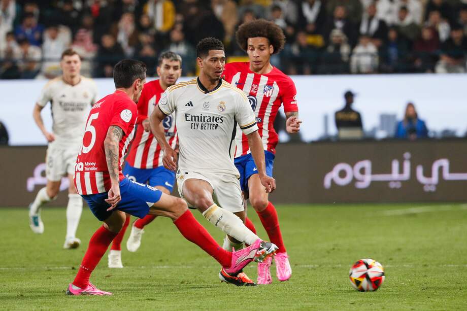 El centrocampista del Real Madrid Jude Bellingham (2-d) juega un balón entre Stefan Savic (i) y Axel Witsel (d), ambos del Atlético de Madrid, durante el partido de semifinales de la Supercopa de España que Real Madrid y Atlético de Madrid disputan este miércoles en el estadio Al Awwal Park de Riad, en Arabia Saudí.