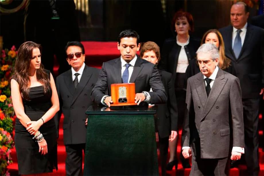 El hijo mayor de Juan Gabriel, Iván Aguilera (c), acompañado de su esposa, Simona Hakman (i), sostiene las cenizas de su padre durante homenaje de dos días en el Palacio de Bellas Artes de Ciudad de México (México). / Agencia EFE