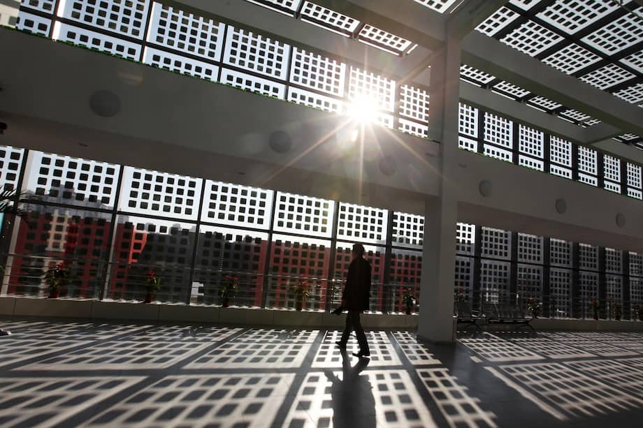 Un hombre camina dentro de un edificio con ventanas de vidrio con paneles solares en la ecociudad chino-singapurense de Tianjin, en la Nueva Área de Tianjin Binhai, China, el 30 de noviembre de 2011 (reeditado el 26 de enero de 2026).