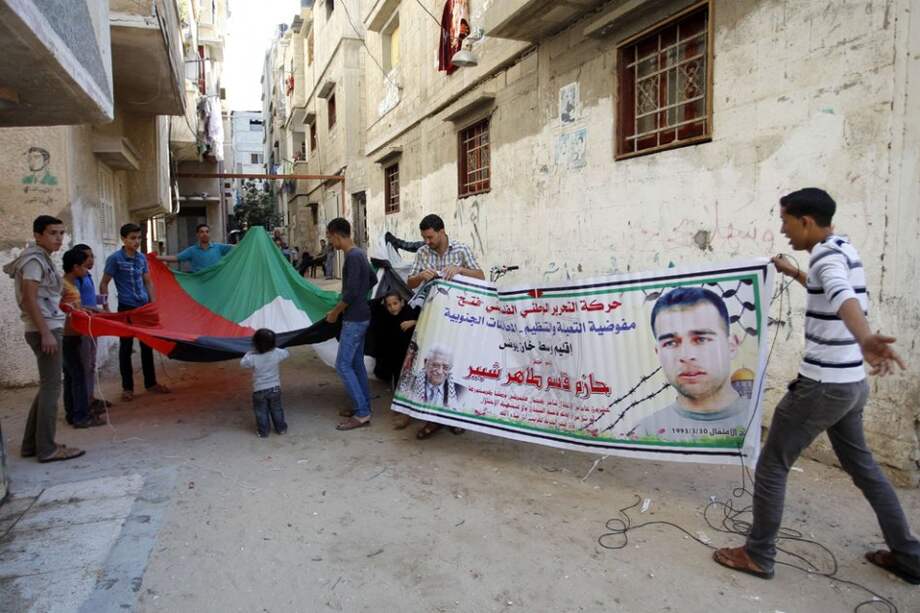 Familiares del preso palestino, Hazem Shobair, aguardan su libertad con pancartas./ AFP
