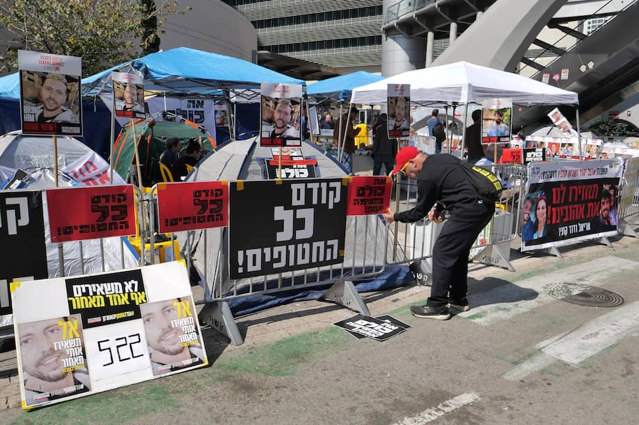 Un manifestante cuelga carteles junto a tiendas de campaña cerca de una de las entradas al cuartel general militar de Kirya durante una protesta de las familias de los rehenes israelíes.