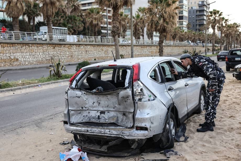 Un policía inspecciona un automóvil dañado en el lugar de un ataque aéreo israelí en la zona costera de Ramlet al-Bayda en Beirut, la madrugada del 12 de marzo de 2026.