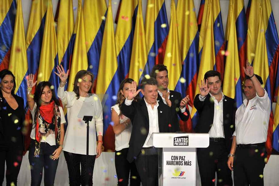 El reelegido presidente Juan Manuel Santos y el vicepresidente electo Germán Vargas Lleras celebran con sus familias y con la palabra paz escrita en la palma de sus manos. / Gustavo Torrijos - El Espectador
