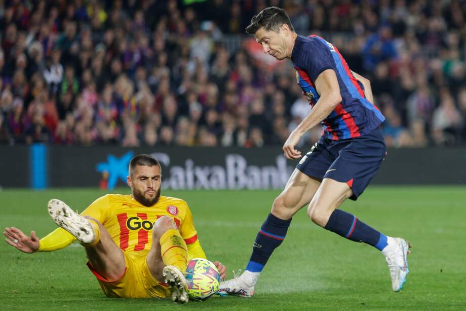 El delantero polaco del FC Barcelona Robert Lewandowski (der.) lucha con el defensa del Girona FC David López Silva (izq.) durante el partido de fútbol de la jornada 28 de LaLiga que FC Barcelona y Girona FC juegan este lunes en el Camp Nou.