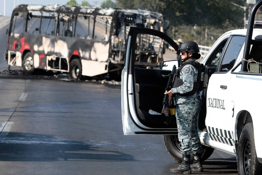 Un miembro de la Guardia Nacional se encuentra cerca de un autobús incendiado por grupos del crimen organizado, en respuesta a un operativo en Jalisco, México, para detener a un objetivo de seguridad prioritario.