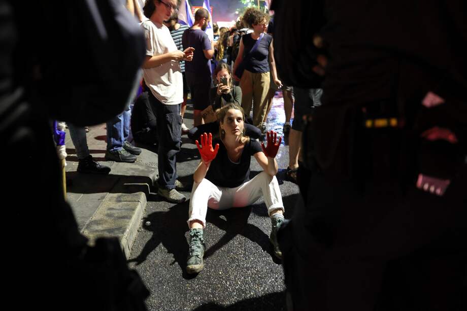 Una mujer con las manos manchadas de rojo se manifiesta junto a los partidarios de las familias de los rehenes retenidos por Hamás en Gaza, frente a la residencia del primer ministro israelí, Benjamin Netanyahu, en Jerusalén.