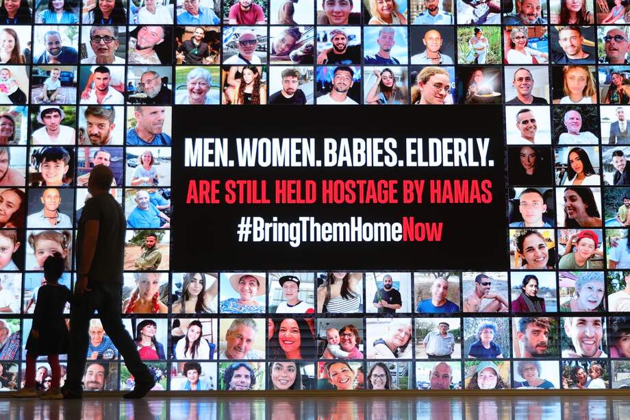 En Tel Aviv, la gente pasa junto a un cartel que muestra fotografías de personas secuestradas por Hamás.