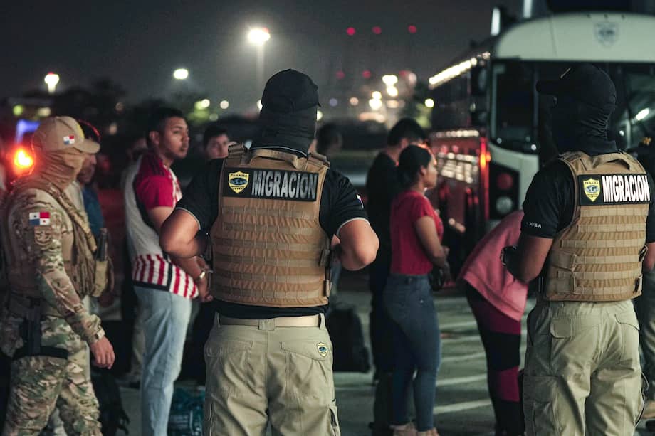 Oficiales de migración protegen a ciudadanos colombianos mientras esperan ser deportados en el aeropuerto de Albrook Gelabert en la ciudad de Panamá el 17 de mayo.