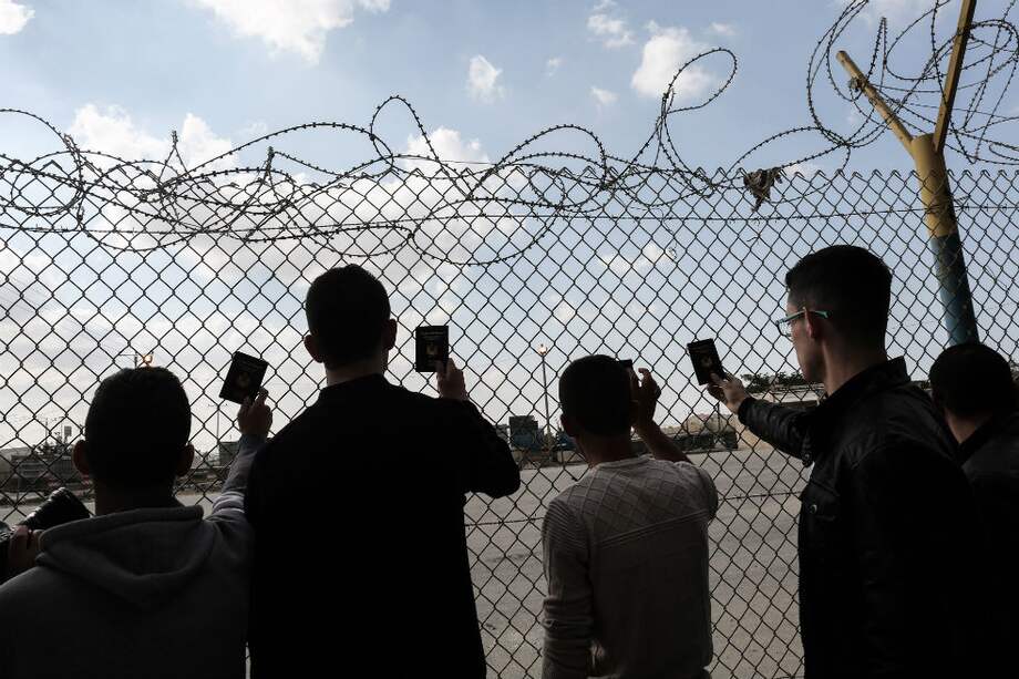 Jóvenes palestinos muestran sus pasaportes en la frontera con Egipto. / AFP