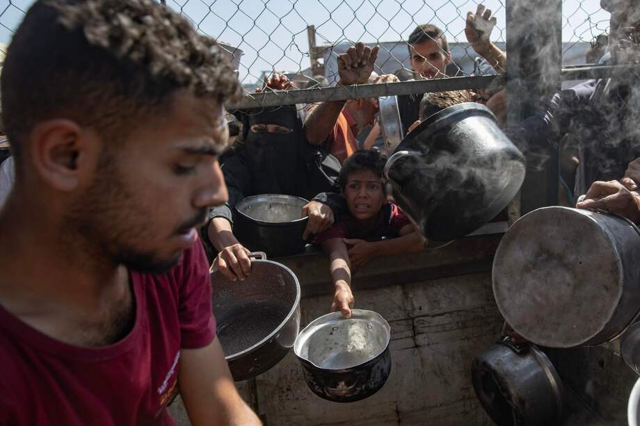 Palestinos desplazados internos se reúnen frente a una cocina benéfica para recibir raciones limitadas en medio de la escasez de alimentos, en Khan Younis.