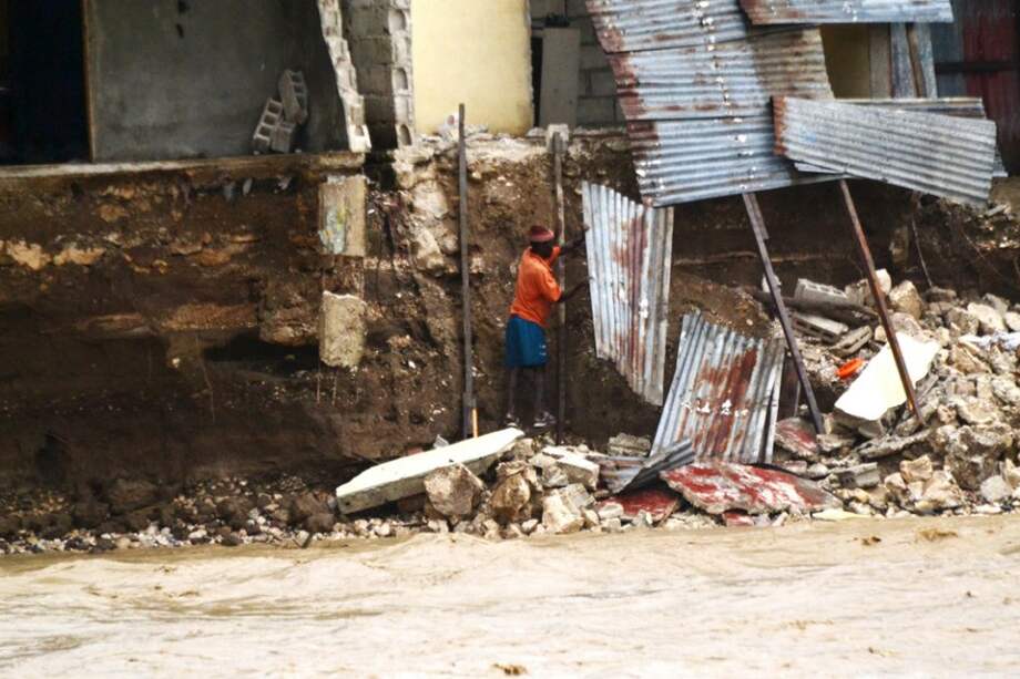 Un hombre levanta escombros frente a su casa que se vio afectada por las aguas de un río desbordado en Puerto Príncipe/ EFE