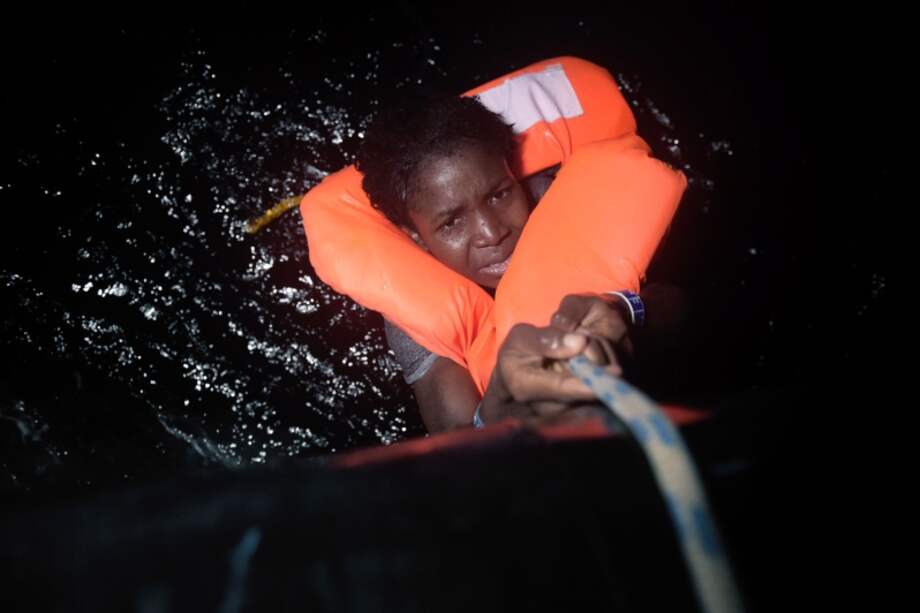 Una migrante que salió de las costas de Libia es rescatada en el Mediterráneo. / AFP