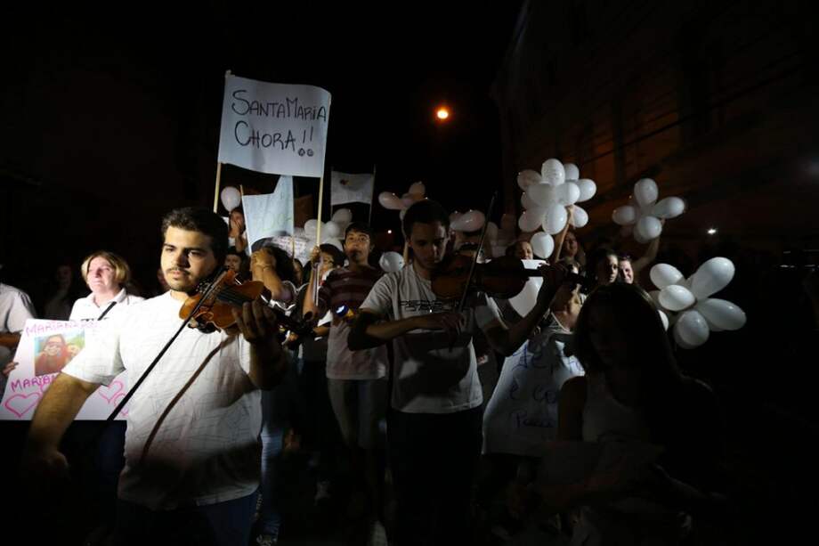 Un grupo de músicos tocan junto a miles de personas que se congregaron en una plaza del centro de la ciudad brasileña de Santa María para rendir un homenaje silencioso a las víctimas del incendio./ EFE