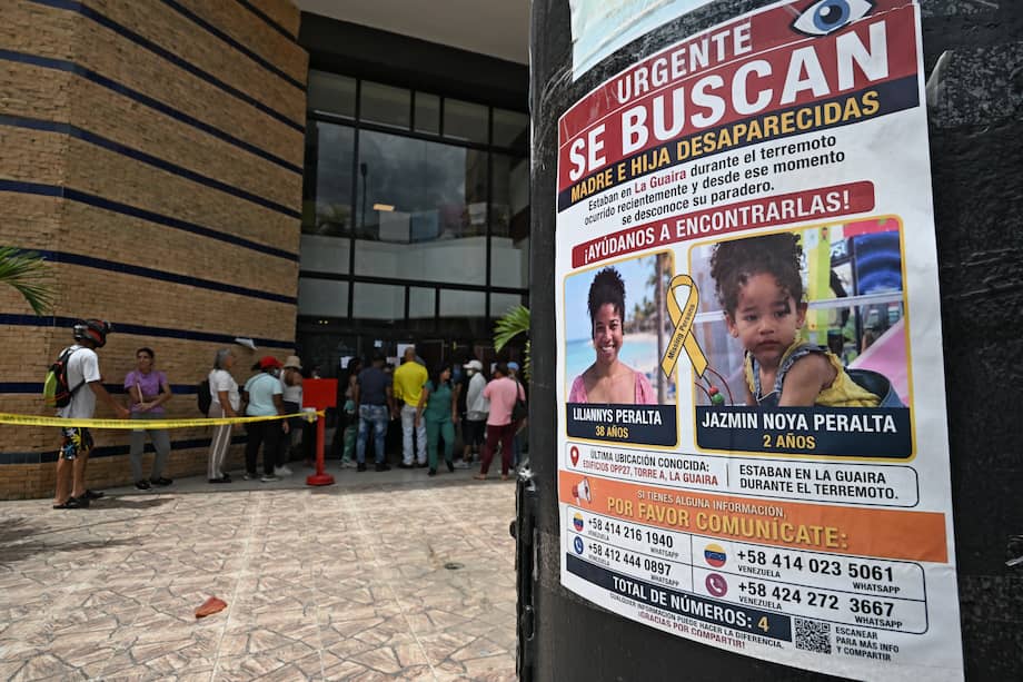 Vista de un letrero que muestra a las personas desaparecidas mientras la gente hace fila afuera de un McDonald's utilizado como hospital de campaña después de los terremotos del 24 de junio en Caraballeda.
