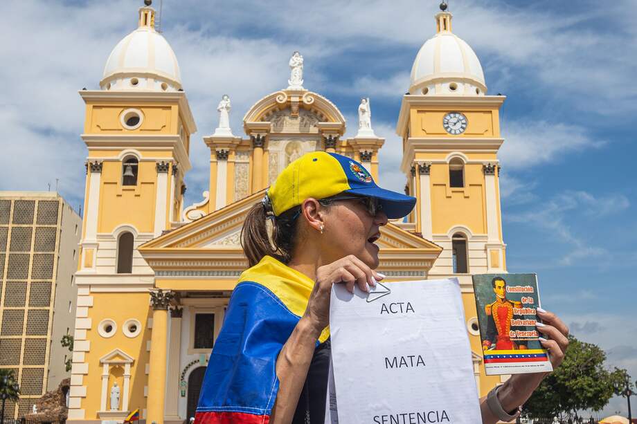Una mujer sostienen una bandera y documentos durante una protesta convocada por María Corina Machado este miércoles, frente a la Basílica de nuestra señora de Chiquinquirá, en Maracaibo (Venezuela).