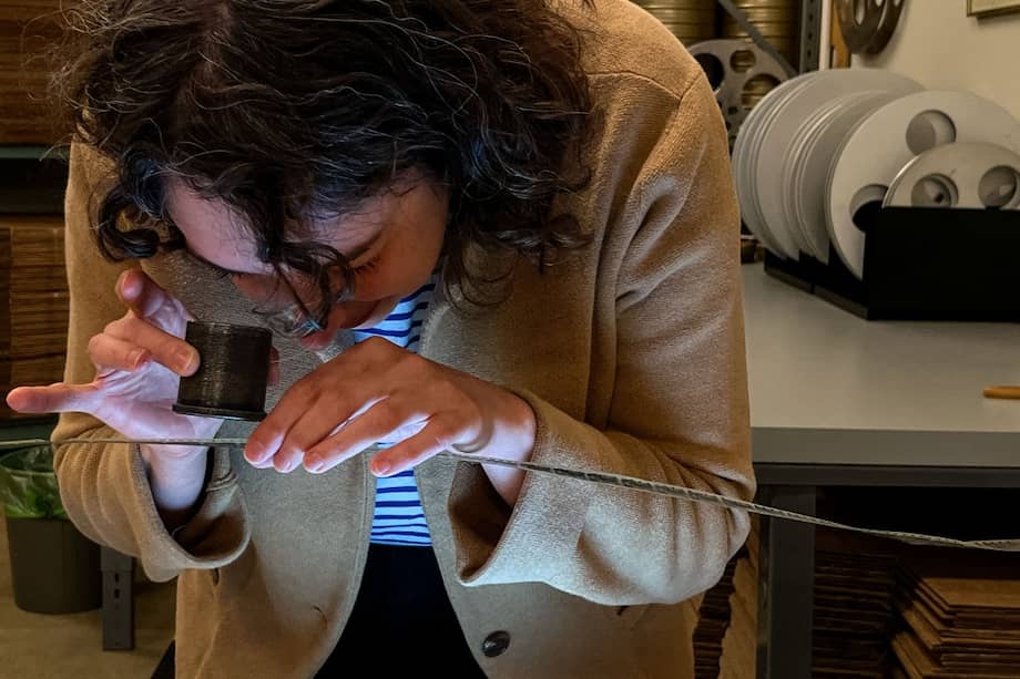 La técnica de la bóveda de películas de nitrato, Courtney Holschuh, utilizando una lupa, observa la película original del cortometraje mudo francés de Georges Méliès de 1897, "Gugusse et l'Automate", en un espacio de trabajo en la bóveda de películas de nitrato en el Campus Packard de la Biblioteca del Congreso. Conservación Audiovisual Nacional.