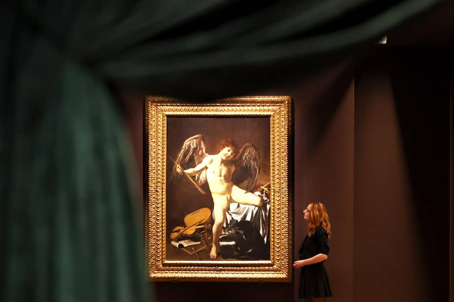 Foto de referencia: Un galerista posa con la obra «Cupido Victorioso» (1601-1602) del artista italiano Michelangelo Merisi da Caravaggio en la Colección Wallace de Londres.