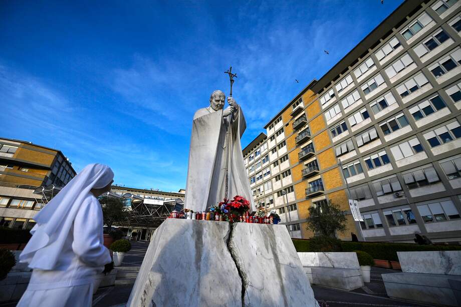 Una monja reza ante la estatua de Juan Pablo II afuera del hospital Gemelli, donde el papa Francisco está internado para recibir pruebas y tratamiento en Roma, Italia.