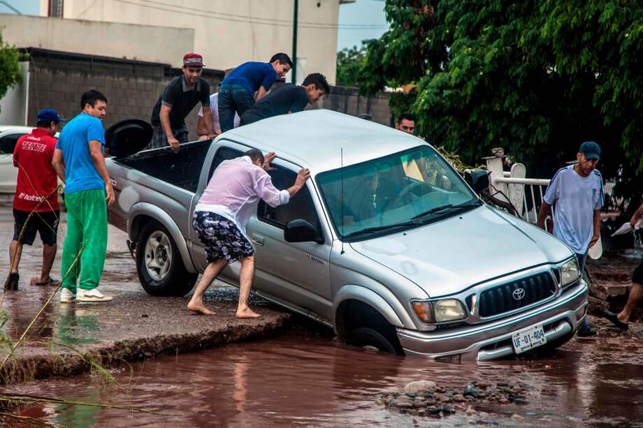 Las fuertes lluvias en Culiacán han causado muchos estragos. La gente intenta salvar sus vehículos y pertenencias. / AFP