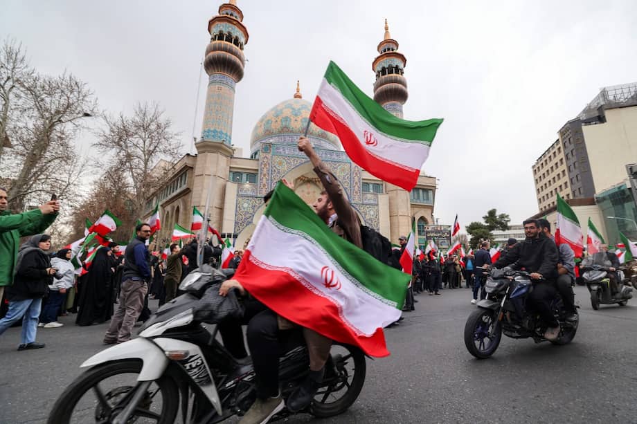 Manifestantes viajan en motocicletas ondeando banderas nacionales iraníes durante una manifestación en Teherán en apoyo al gobierno y contra los ataques estadounidenses.