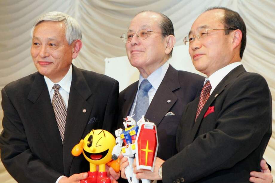 Foto de archivo de mayo de 2005 que muestra al presidente de Namco, Masaya Nakamura (centro), rodeado por Takeo Takasu (derecha), presidente de Bandai, y el vicepresidente de Namco Kyushiro Takagi (izquierda) en una conferencia de prensa en Tokio. /Archivo AFP