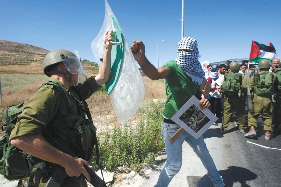 Los muertos en la guerra de Gaza superaron los 13.300. Aquí chocan un palestino y un soldado israelí.