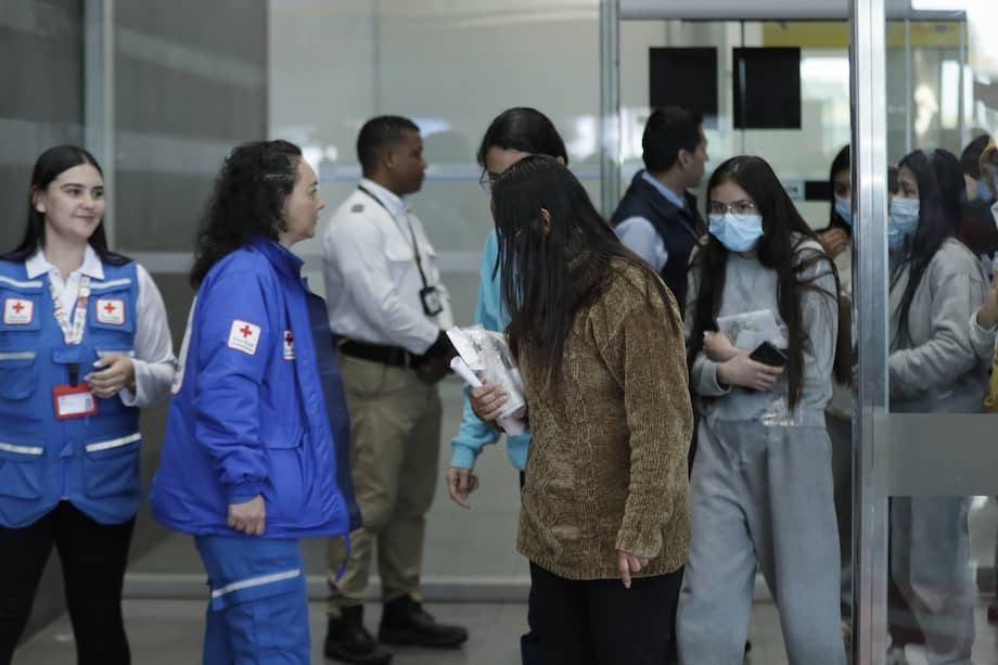 Ciudadanas colombianas deportadas de Estados Unidos caminan frente a funcionarias de la Cruz Roja en el Aeropuerto Internacional El Dorado, en Bogotá (Colombia).