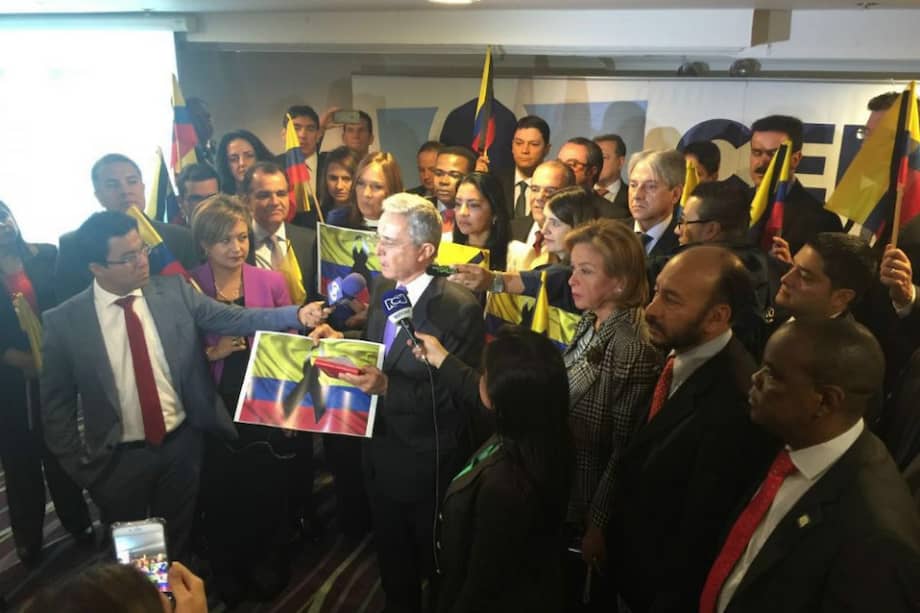 La bancada del Centro Democrático protestando con banderas con una cinta negra anudada en el centro.