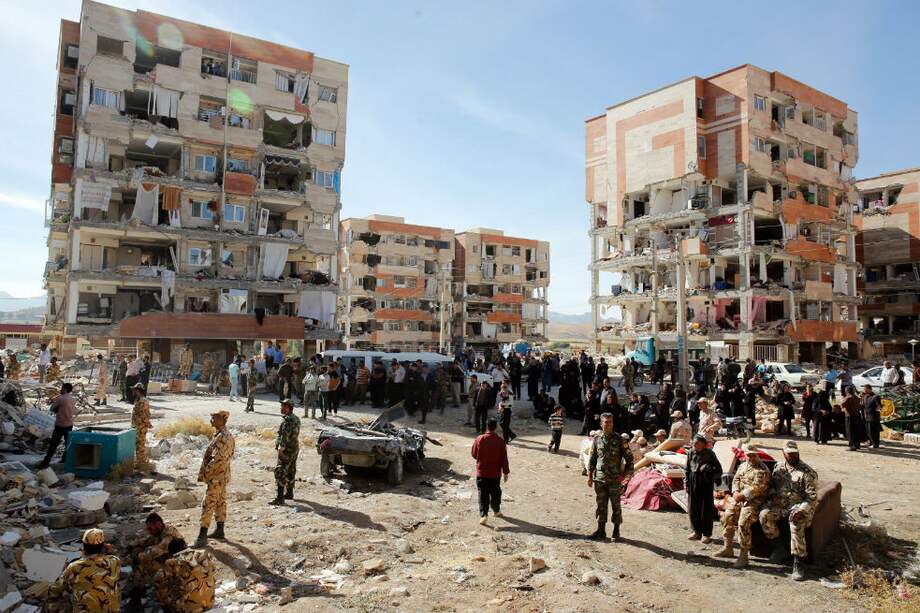 Víctimas del fuerte terremoto de 7,3 grados en la escala de Richter que asoló la provincia de Kermanshah permanecen junto a edificios dañados en la ciudad de Pole-Zahab (Irán). / EFE, ABEDIN TAHERKENAREH