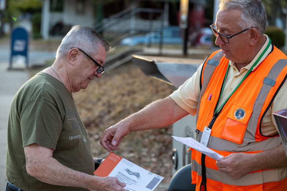Un trabajador electoral explica el proceso de entrega de una boleta de voto por correo mientras un votante se prepara para colocarla en la urna durante el día de las elecciones en Filadelfia, Pensilvania, el 5 de noviembre de 2024.