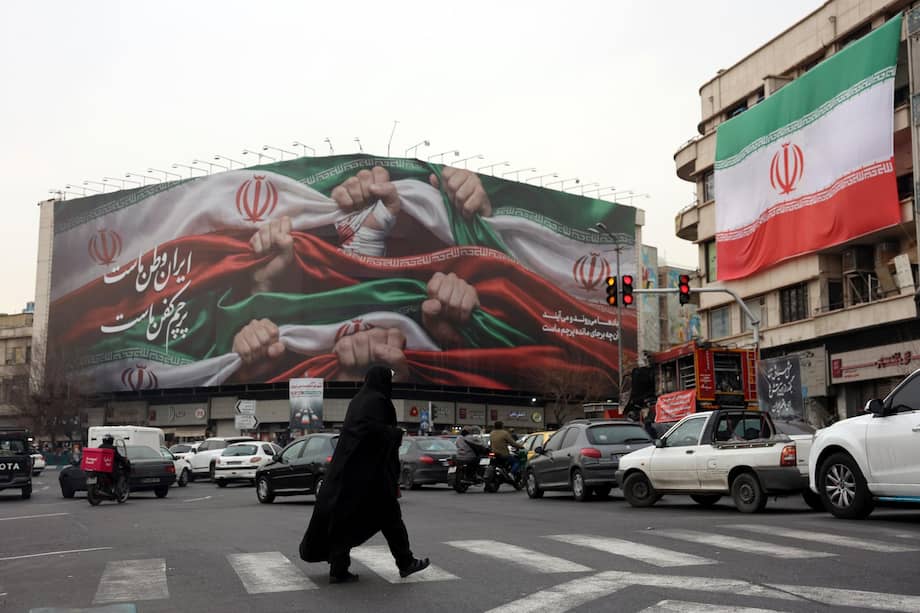 Una mujer cruza una calle cerca de un cartel que dice "Irán es nuestra patria", en la plaza Enqelab de Teherán.