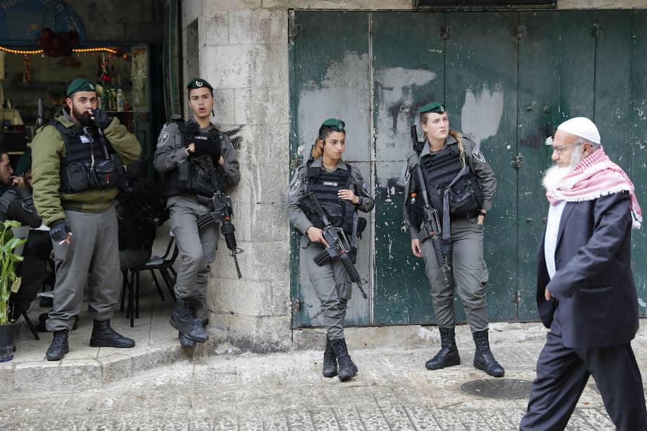 Un palestino camina por la Ciudad Vieja en Jerusalén, custodiada por militares israelíes. / AFP