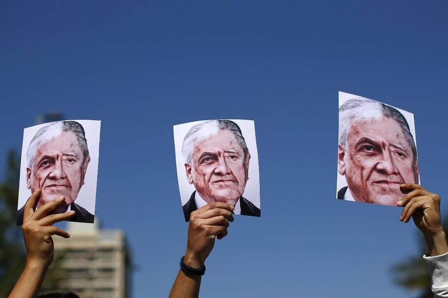 Manifestantes chilenos sostienen afiches con el rostro del presidente Sebastián Piñera mezclado con el del dictador chileno Augusto Pinochet. / AFP