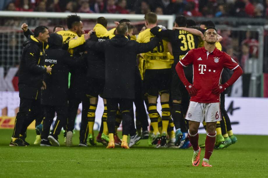 Thiago Alcántara, jugador del Bayern Múnich, se lamenta, mientras los jugadores del Dortmund celebran su clasificación a la final. / AFP