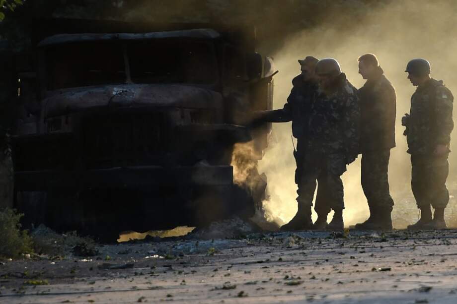 Soldados del ejercito ucraniano revisan uno de los camiones quemados durante el ataque