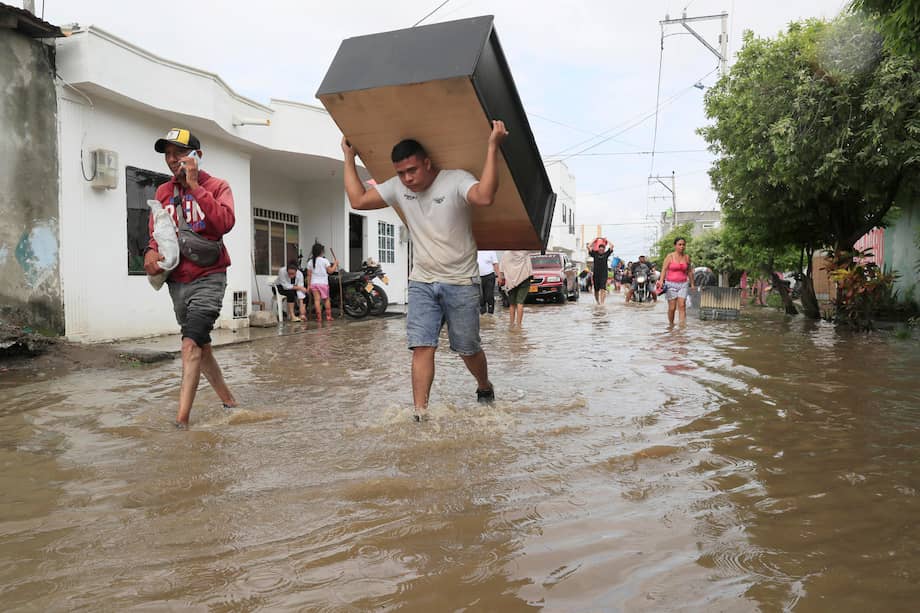 Personas intentan rescatar sus pertenencias este sábado luego de una nueva creciente del río Sinú, en Montería (Colombia).