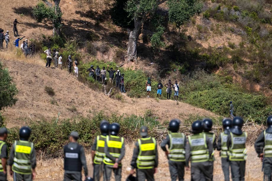 Fuerzas de seguridad marroquíes vigilan los intentos de cientos de migrantes subsaharianos y sudaneses, congregados para entrar en la ciudad española de Ceuta.