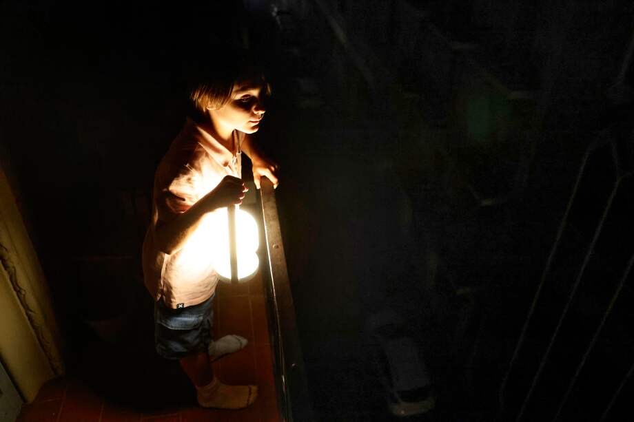 Un niño con una lampara mira desde el balcón la calle todavía a oscuras esta madrugada en el centro de Barcelona durante el corte de suministro eléctrico que afecta este lunes a España y que ha dejado sin servicio el metro y el tranvía de Barcelona y todas las líneas de ferrocarril, y sin red de teléfonos móviles ni internet.