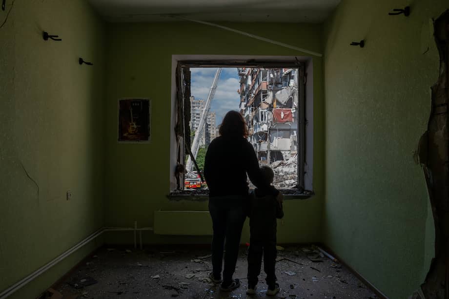Un retrato colaborativo de Janna y su hijo Oliver, de seis años, mientras miran a través de la ventana destrozada de su jardín de infancia hacia un edificio residencial de nueve pisos destruido por un ataque con misiles rusos ocurrido esa misma mañana.
24 personas murieron. Kyiv, Ucrania. 14 de mayo de 2026.