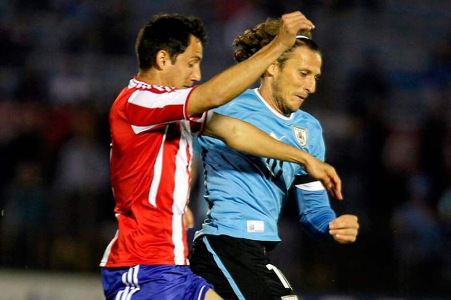 El paraguayo Iván Piríz disputa el balón con Diego Forlán. / EFE