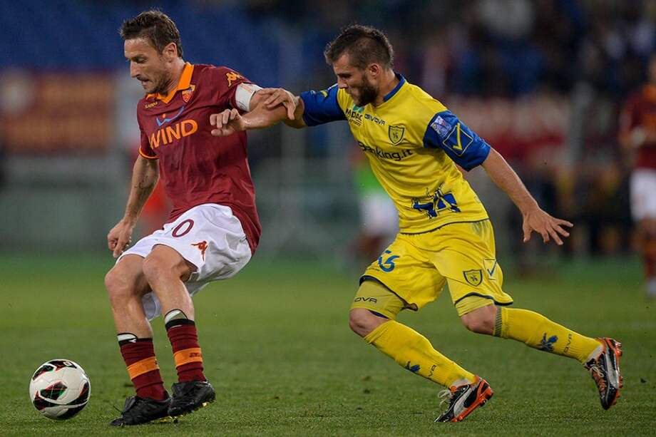 El capitán de la Roma, Francesco Totti, aguanta la marca de Perparim Hetemaj del Chievo Verona. / AFP