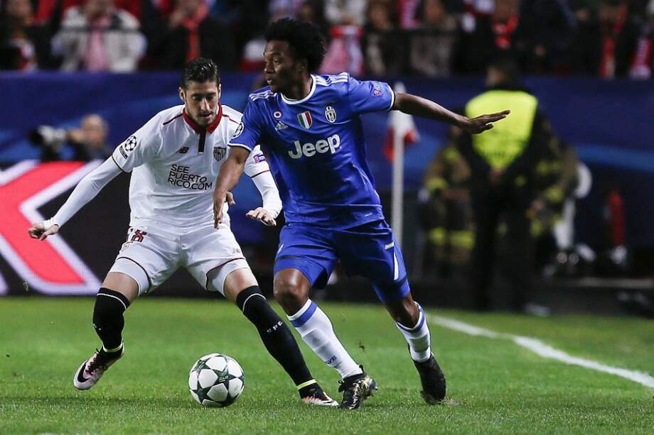 El jugador del Sevilla, Sergio Escudero (i), lucha el balón con el colombiano Juan Guillermo Cuadrado (d), de Juventus, este martes, en la Liga de Campeones. / AFP