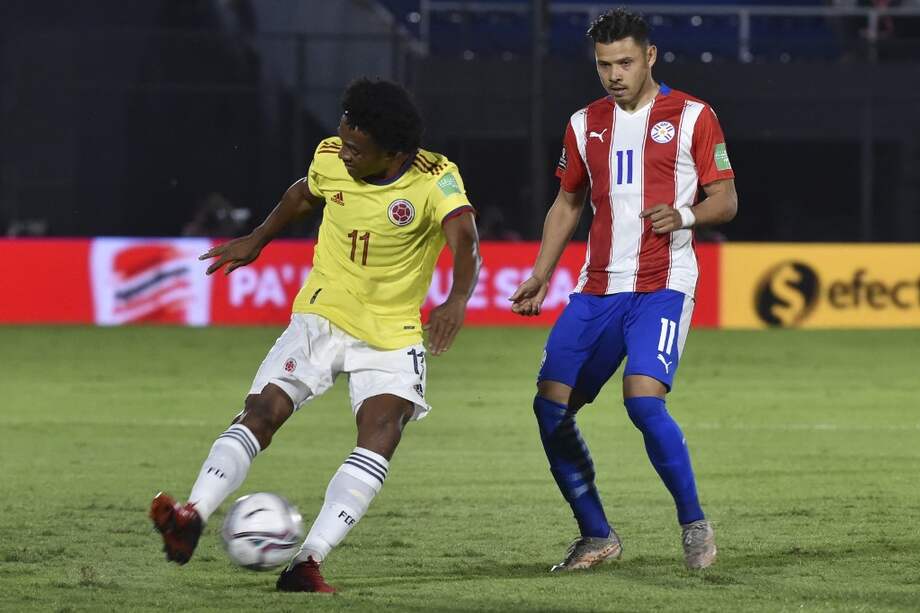 El colombiano Juan Guillermo Cuadrado (izq.) es marcado por Ángel Romero, durante el encuentro ante Paraguay por la eliminatoria al Mundial de Catar 2022.
