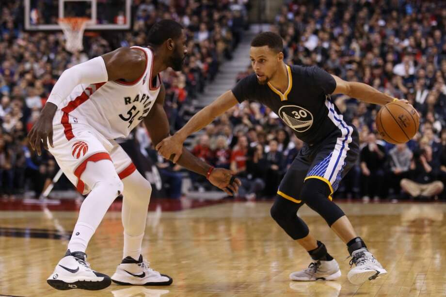 Stephen Curry, número 30 de los Warriors (d), enfrenta a Patrick Patterson, número 54 de los Toronto Raptors. / AFP