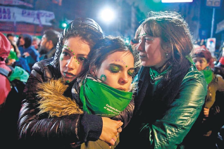 Tres mujeres a favor de la ley del aborto legal se lamentan ante la decisión del Senado. / AFP