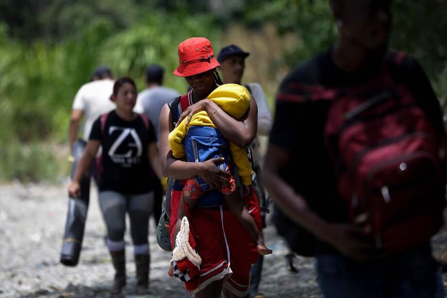 Una persona migrante haitiana carga a su hijo en la selva mientras esperan para ser trasladados en canoa desde la Quebrada León hasta a la comunidad de Bajo Chiquito, el 10 de marzo de 2023, en Darién (Panamá).