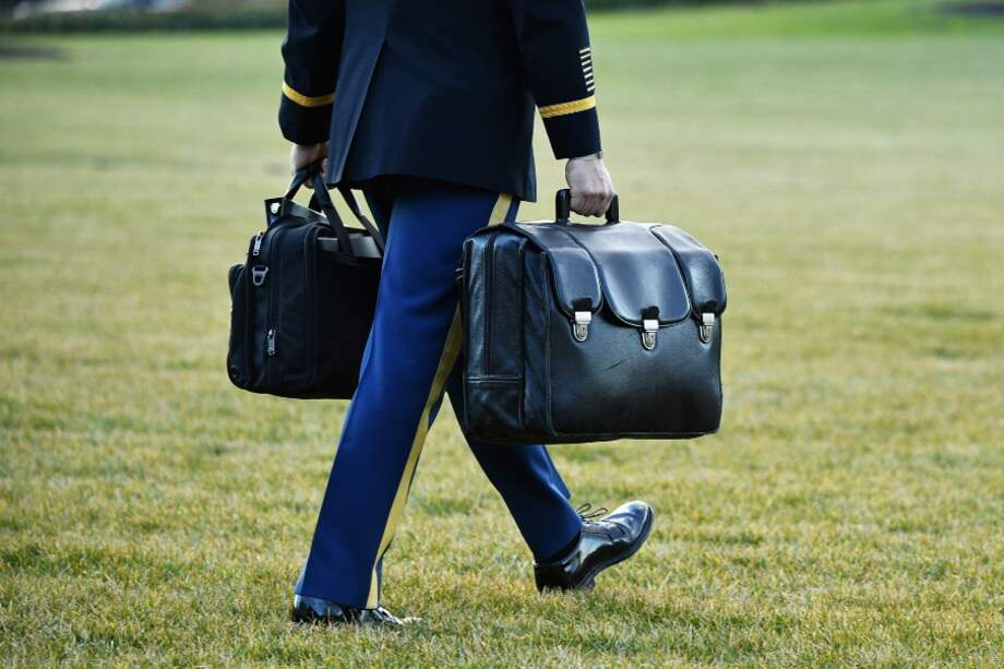 Un ayudante militar lleva el maletín -conocido como "balón nuclear" al helicóptero que abordó ayer Donald Trump antes de dejar la Casa Blanca.