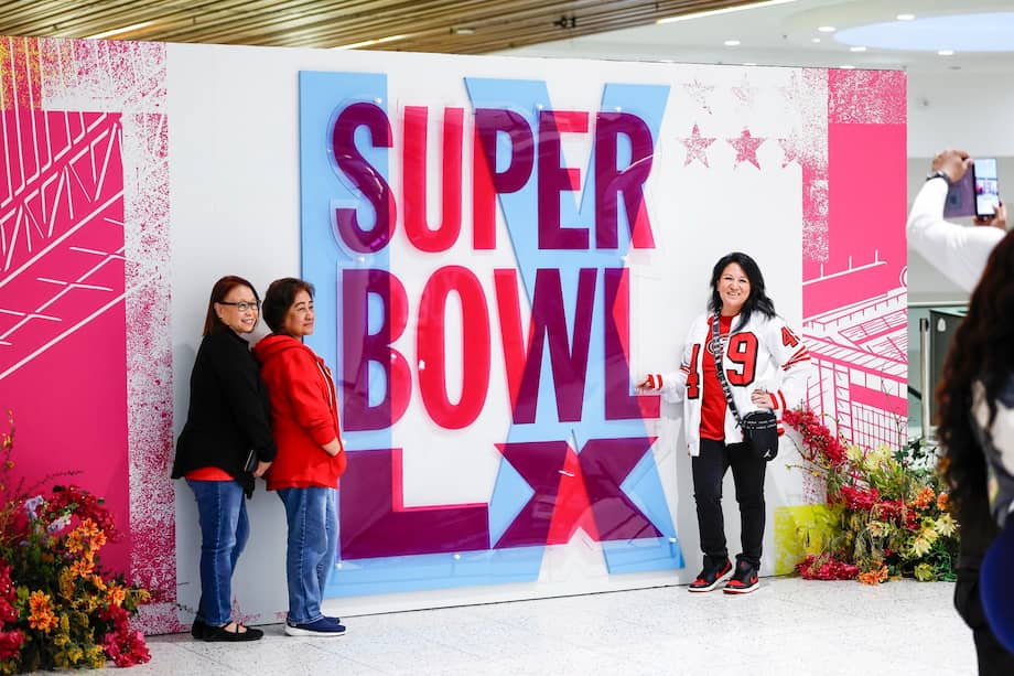 Fans de fútbol americano se toman una foto con el letrero del Super Bowl LX.